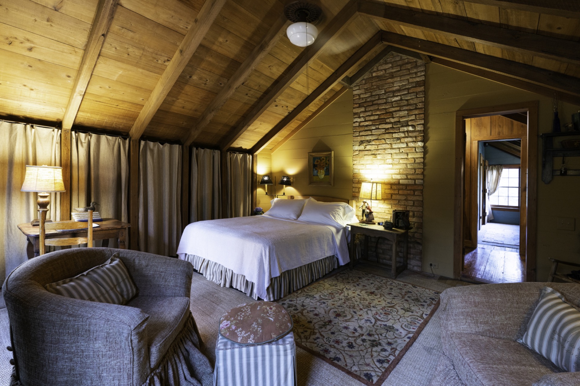 A lamplit timber attic suite — exposed beams and warm evening light