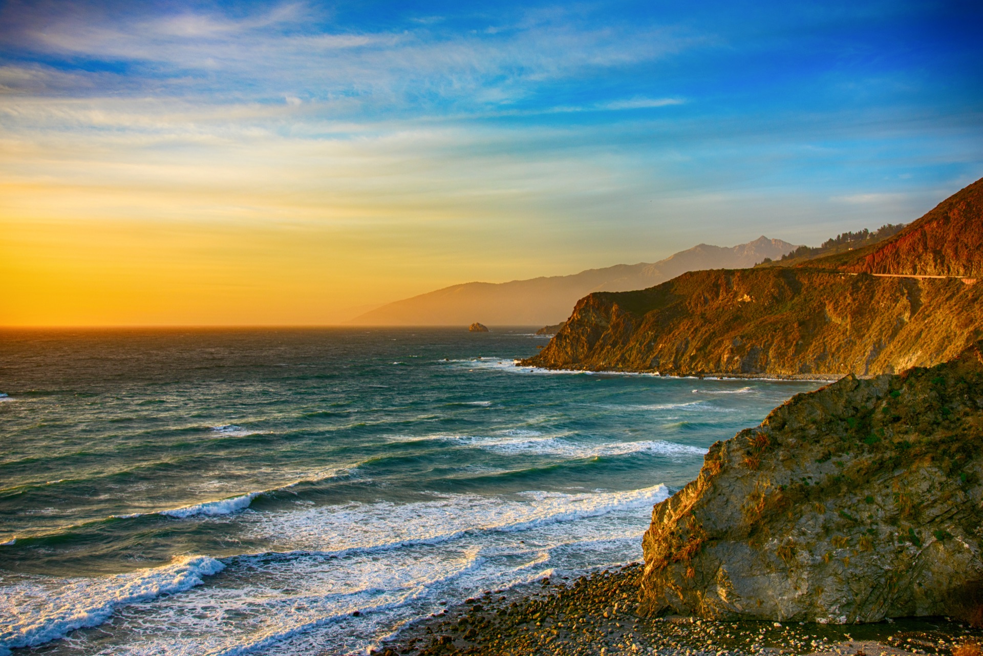 Golden evening light along the Pacific coast — surf below the headlands